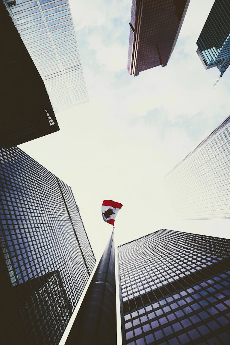 Dramatic low angle view of skyscrapers surrounding a Canadian flag in downtown Toronto.